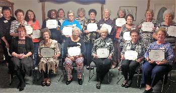 Six ladies sitting in chairs, 13 ladies standing, and all holding certificates.